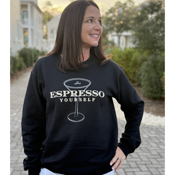 Woman wearing a black sweatshirt with 'Espresso Yourself' text and coffee cup graphic.