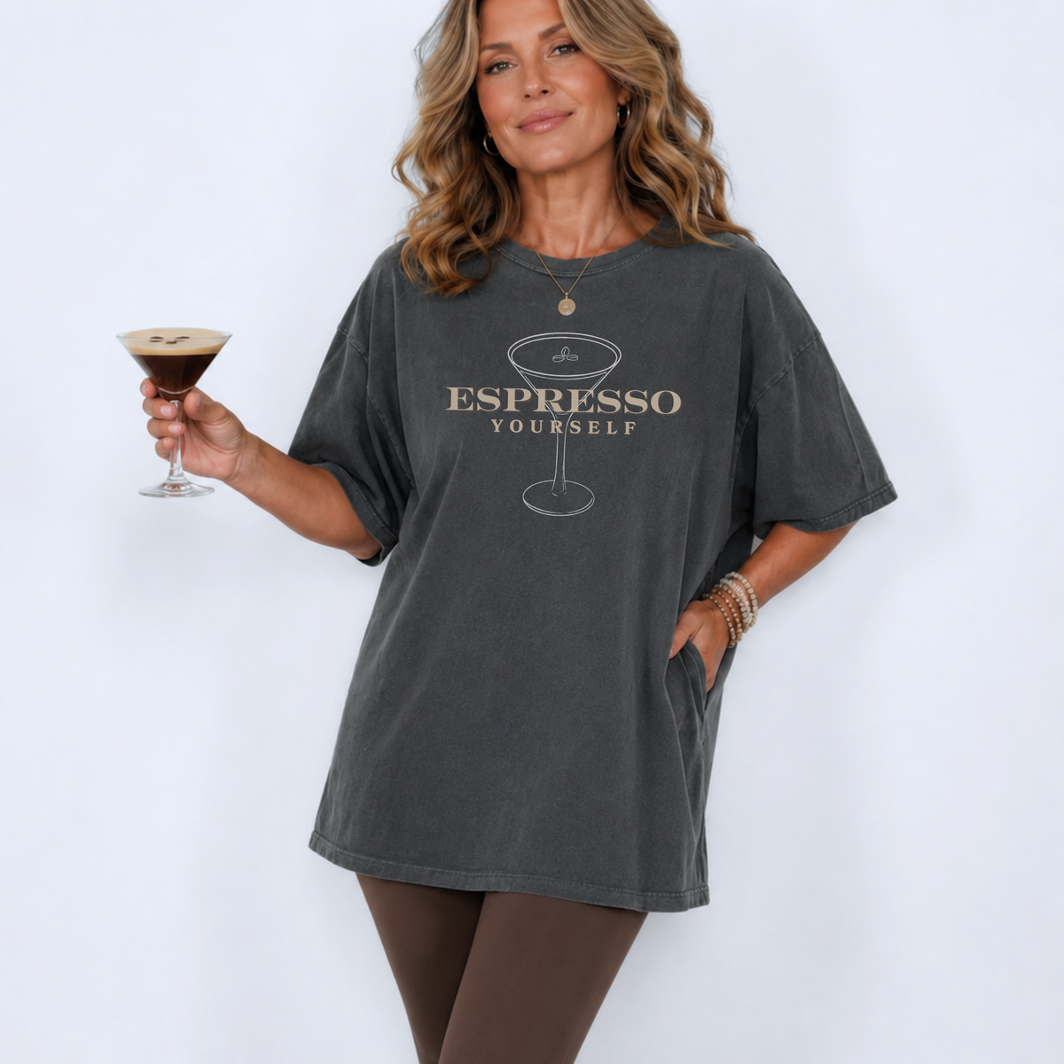 Woman wearing a gray t-shirt with 'Espresso Yourself' text, holding a glass of espresso martini.