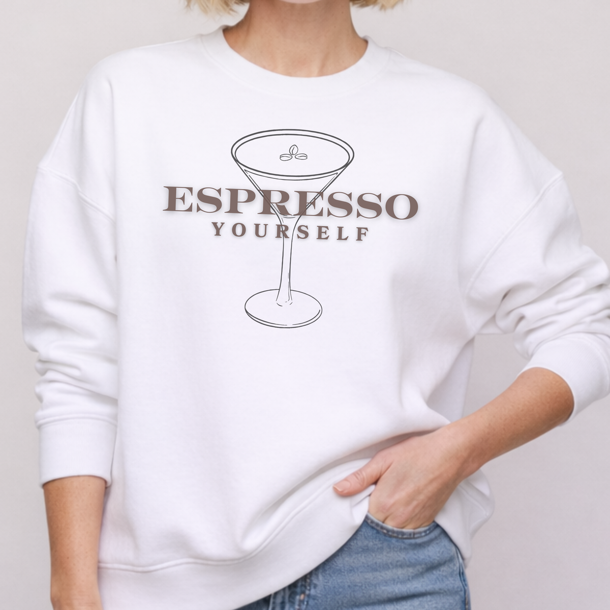 White sweatshirt with 'Espresso Yourself' text and martini glass graphic on a plain background