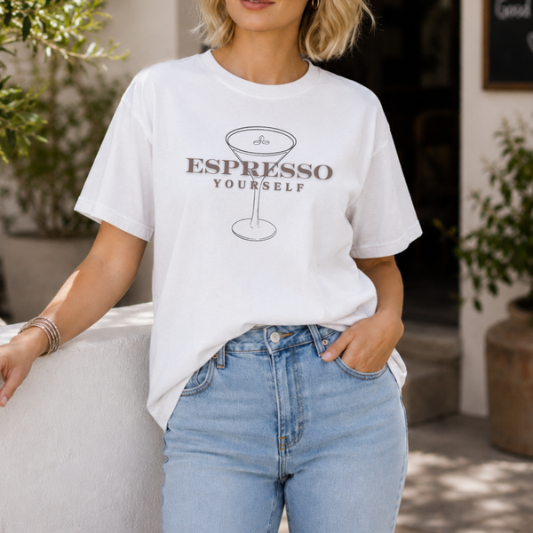 Person wearing a white t-shirt with 'Espresso Yourself' text and graphic, standing outdoors.