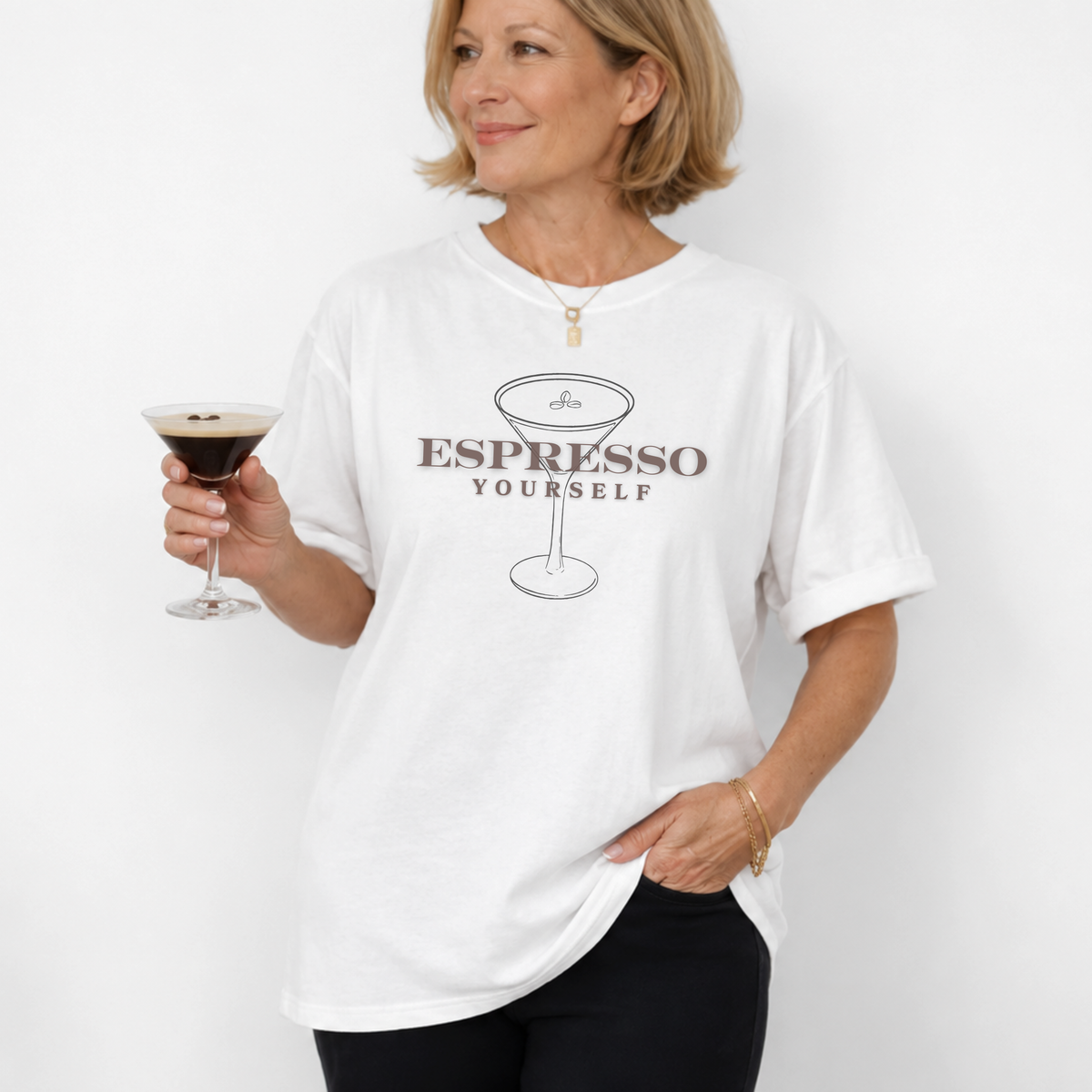 Woman wearing a white t-shirt with 'Espresso Yourself' text, holding an espresso martini.