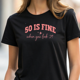 Person wearing a black t-shirt with pink text '50 IS FINE when you look 29'.