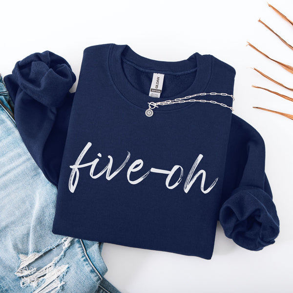 Navy blue folded sweatshirt with 'five oh' text on a white background