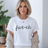 Woman wearing a white Comfort Colors t-shirt with 'five-oh' text in a home setting