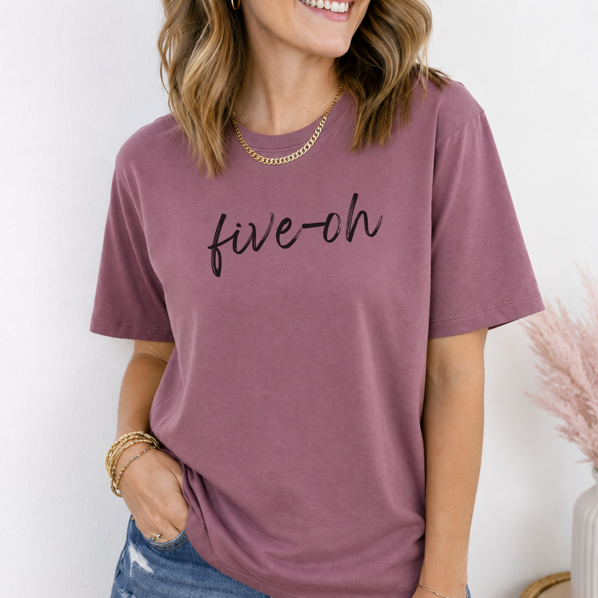 Person wearing a mauve t-shirt with 'five-oh' text on a white background