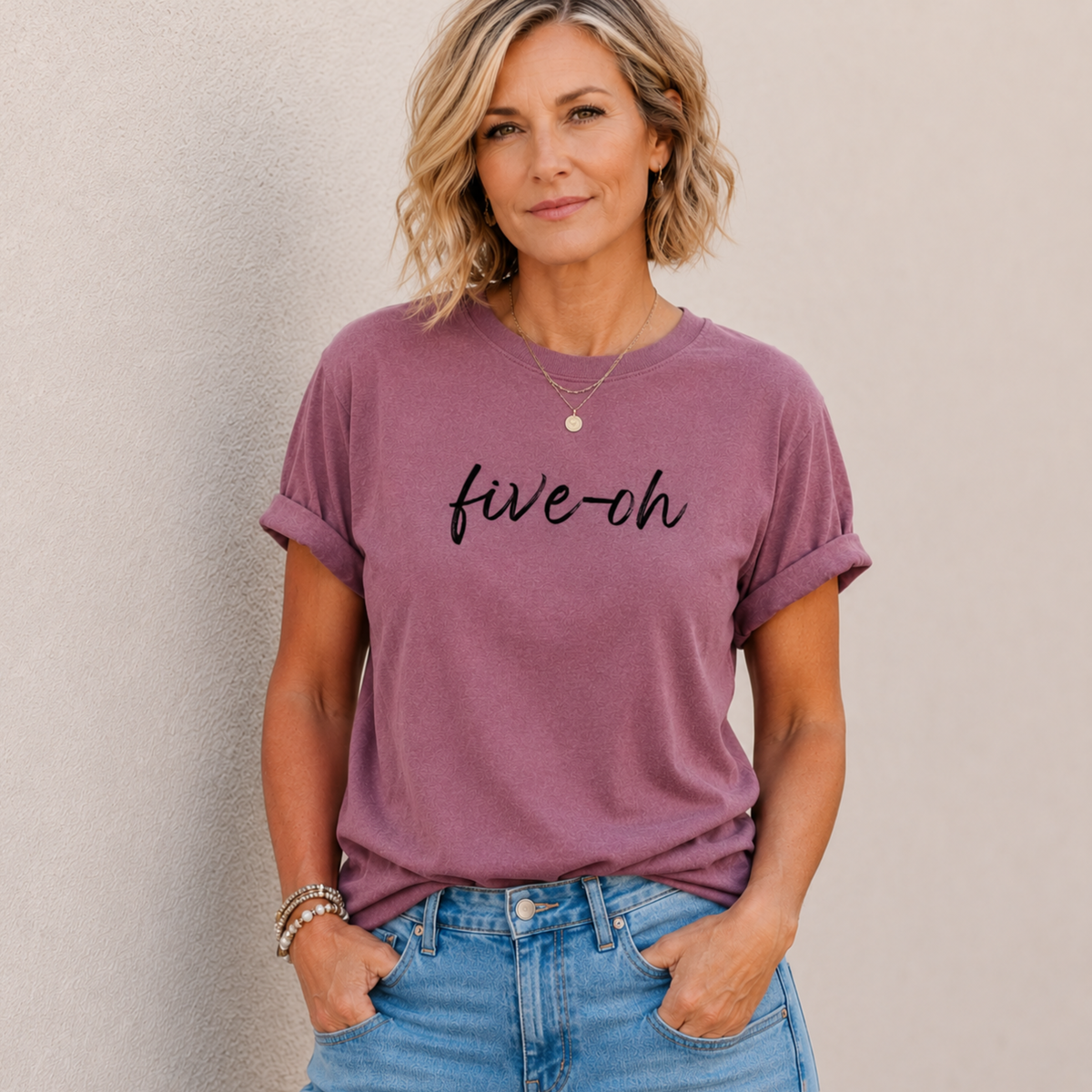 Woman wearing a berry purple t-shirt with 'five-oh' text against a plain background