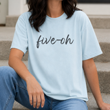 Person wearing a light blue t-shirt with 'five-oh' text, sitting on steps.