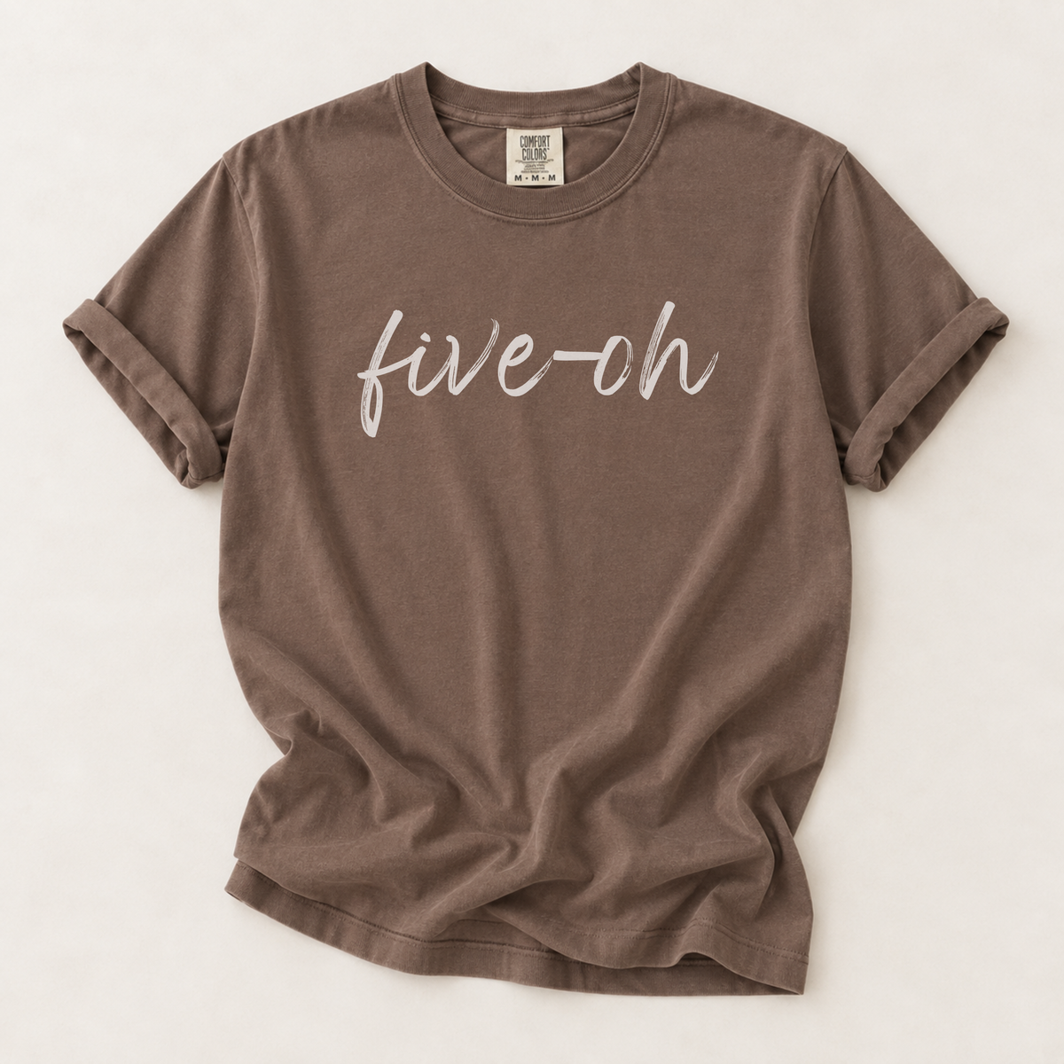 A brown short-sleeve t-shirt with 'five-oh' printed in white script across the chest, laid flat on a light beige background.