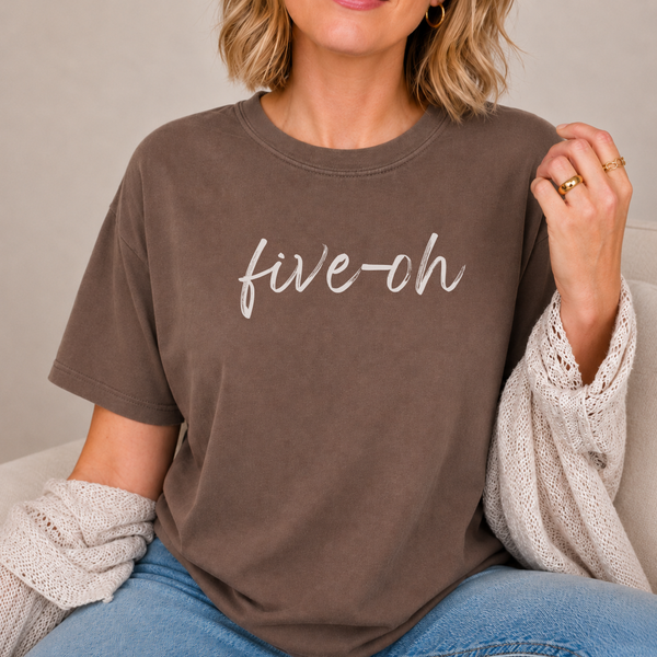 A woman in a espresso brown shirt with the words "five oh" written in script font.