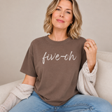 A woman sitting indoors with a espresso brown colored Comfort Colors shirt on with the words 
