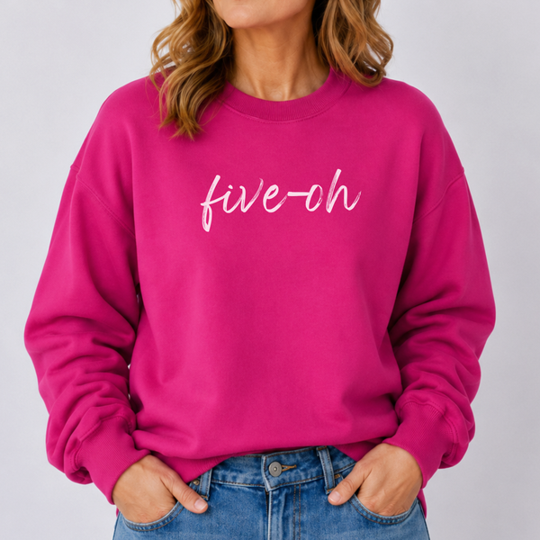 Person wearing a bright pink sweatshirt with 'five-oh' text on a plain background