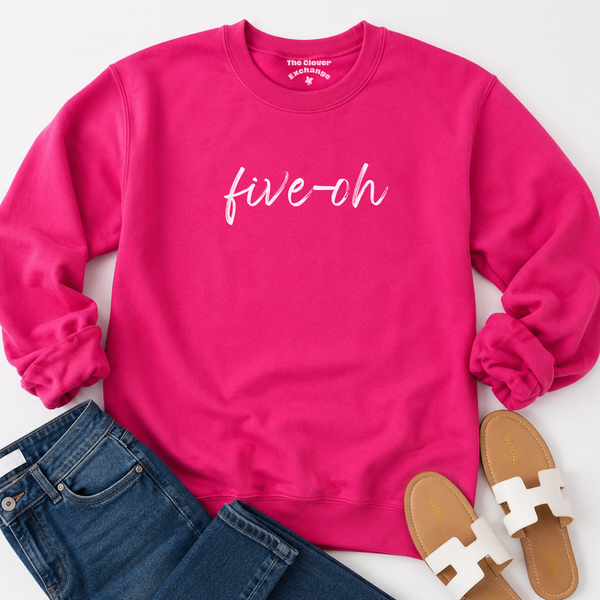 Pink sweatshirt with 'five-oh' text, paired with jeans and sandals on a white background