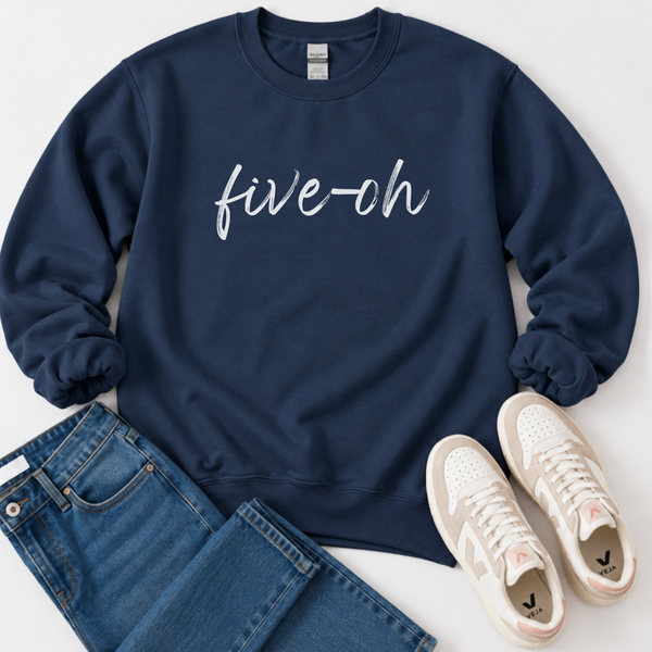 A navy blue crewneck sweatshirt with 'five-ch' written in white script across the chest, styled in a flat lay with blue jeans and white sneakers on a light gray background.