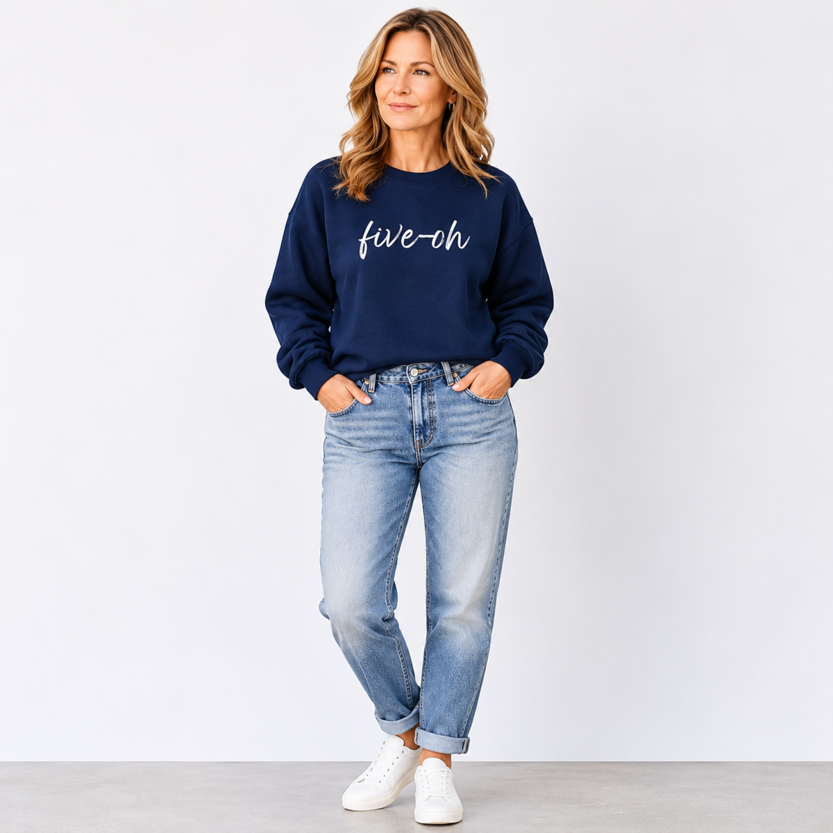 Woman wearing a navy sweatshirt with 'five-oh' text and light blue jeans on a white background