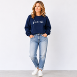 Woman wearing a navy sweatshirt with 'five-oh' text and light blue jeans on a white background