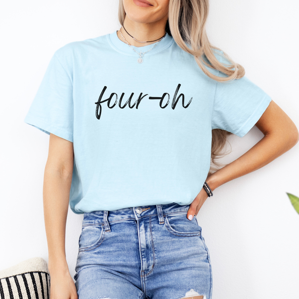 Person wearing a light blue t-shirt with 'four-oh' text and jeans on a white background
