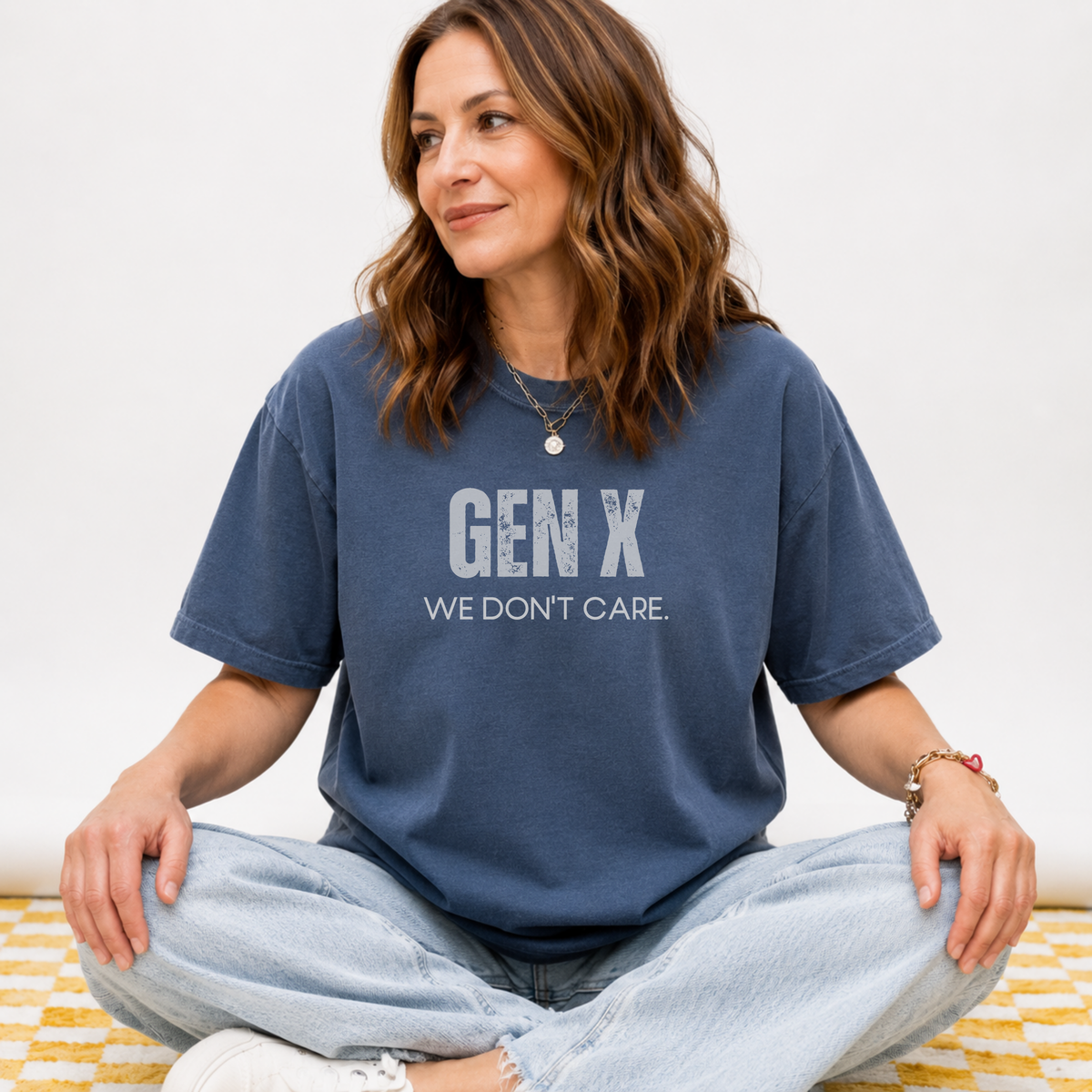 A woman sitting in a navy blue tee shirt on that says "Gen X: We Don't Care."