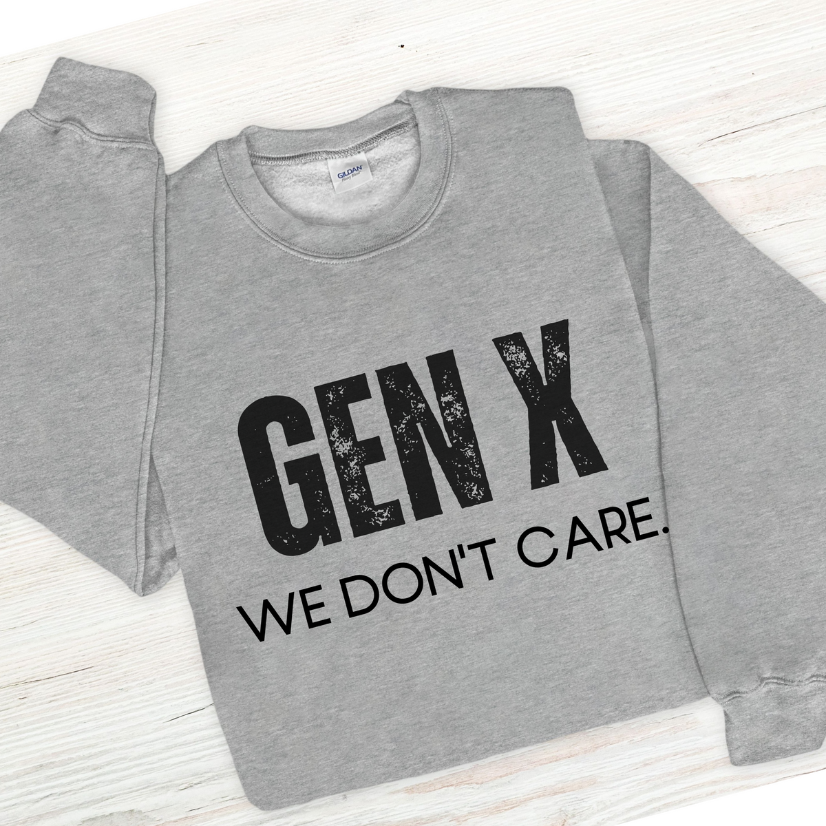 Gray sweatshirt with 'GEN X WE DON'T CARE' text on a light wooden surface