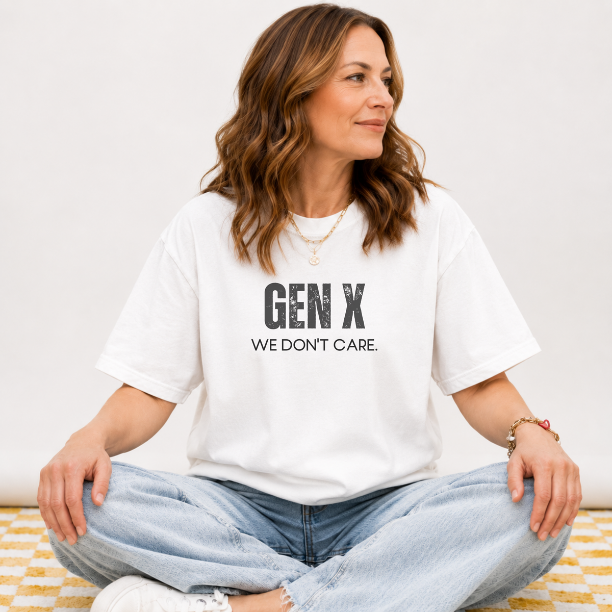 A woman sitting in a white tee shirt on that says "Gen X: We Don't Care."