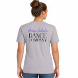 A woman viewed from the back wearing a light gray short-sleeve T-shirt with purple and black text reading 'Denise Sabala DANCE COMPANY' on the back, paired with blue jeans against a plain white background.