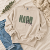 A cream-colored crewneck sweatshirt with 'HARD Pass' printed on the front, styled in a flat lay with blue jeans, a green eucalyptus sprig, and a beige knit blanket.