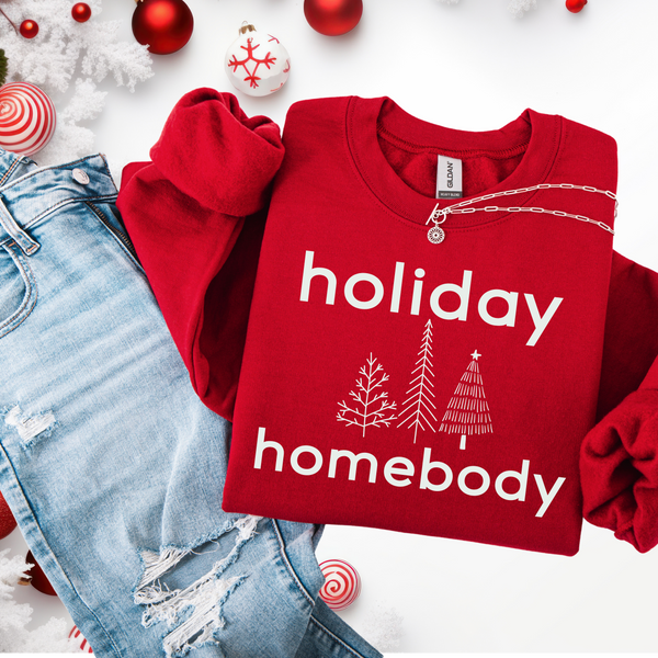 Red sweatshirt with 'holiday homebody' text and Christmas-themed decorations on a white background