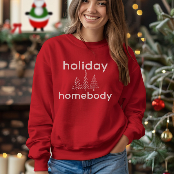 Person wearing a red 'holiday homebody' sweatshirt in a festive setting with Christmas decorations.