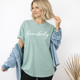 Woman wearing a light green 'homebody' t-shirt with an open denim jacket.