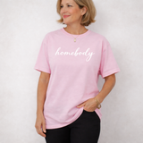 A woman standing with a light pink shirt on that says 