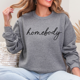 Person wearing a gray sweatshirt with 'homebody' text, sitting indoors.