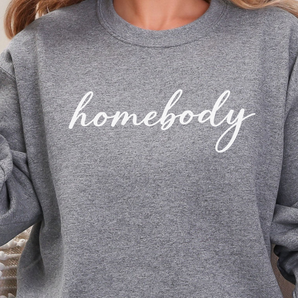A woman in a graphite heather sweatshirt that says "homebody" in white script
