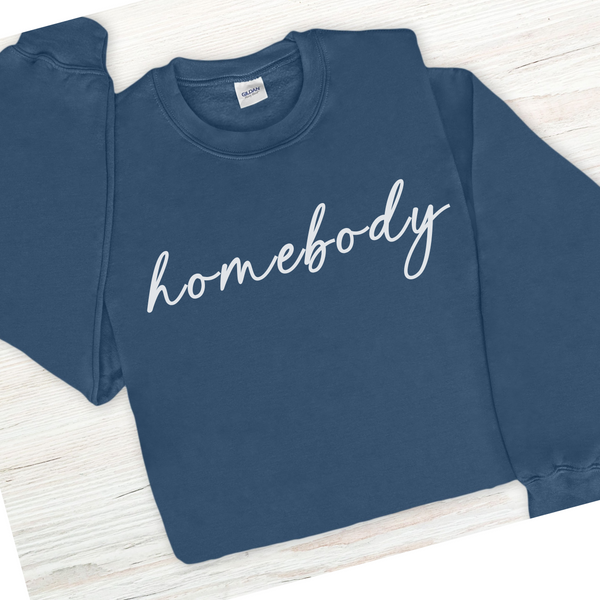 Blue sweatshirt with 'homebody' text on a wooden surface