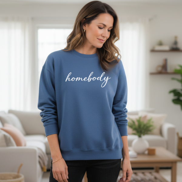 Woman wearing a blue 'homebody' sweatshirt in a living room setting