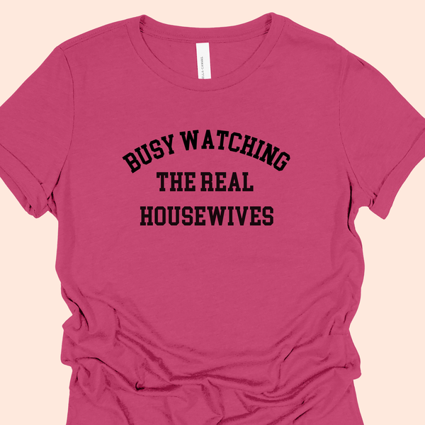 Berry Pink Tee with black lettering that reads "Busy Watching the Real Housewives."