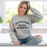 Woman wearing a gray sweatshirt with with the words 