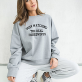 Woman wearing a gray sweatshirt with the words 