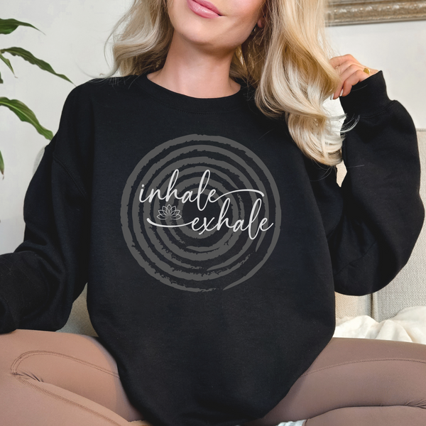 Person wearing a black sweatshirt with 'inhale exhale' over a faded circle design.