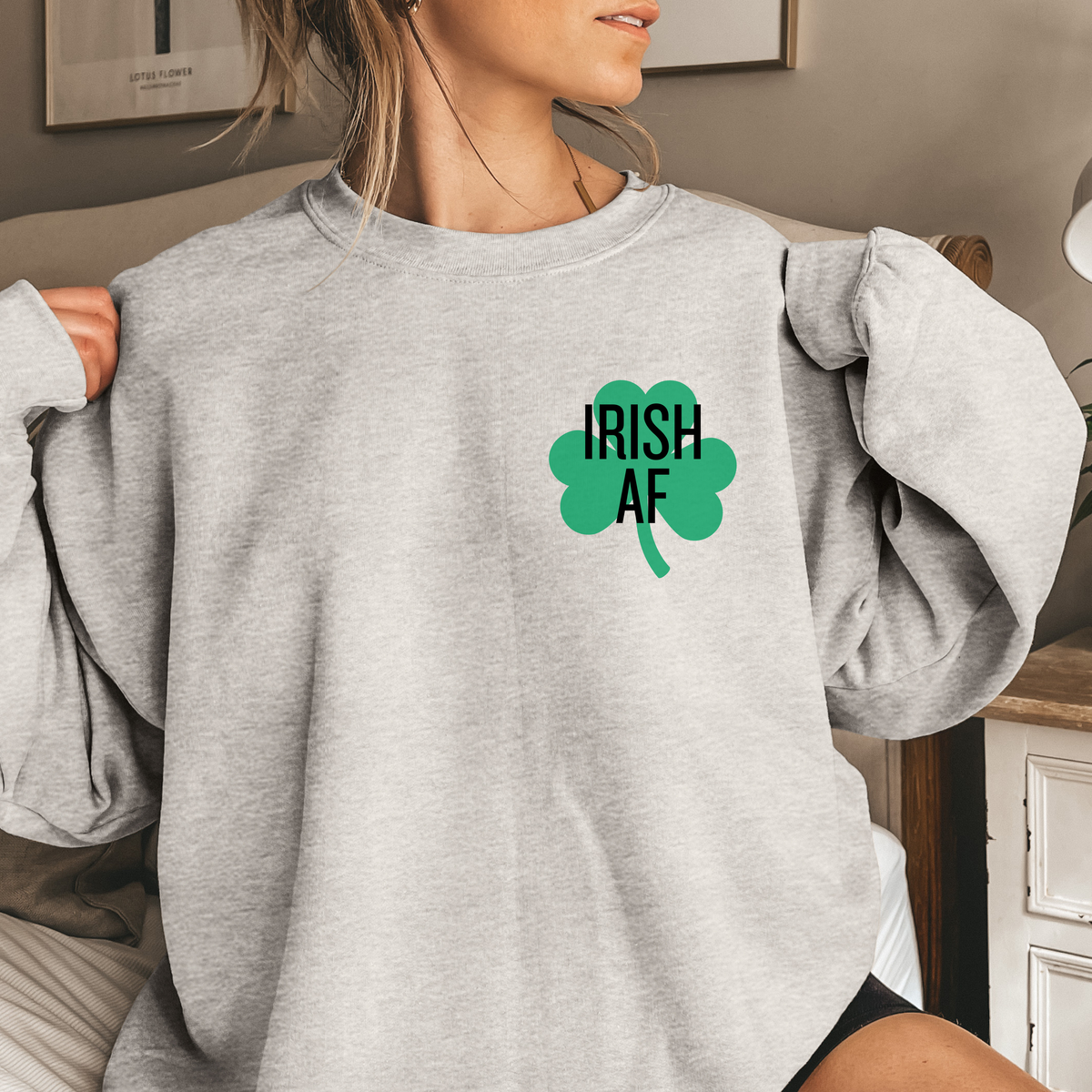 Woman wearing a gray sweatshirt with 'Irish AF' design