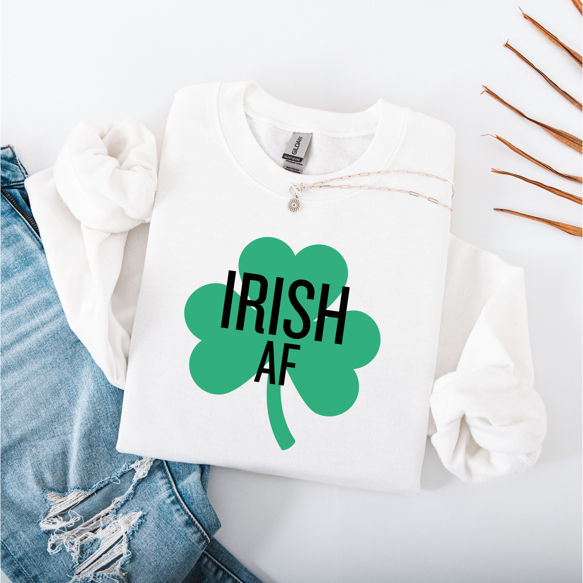 A White folded sweatshirt with green shamrock and 'IRISH AF' text on a white background