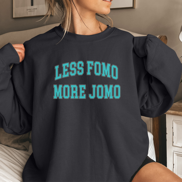 Person wearing a black sweatshirt with 'LESS FOMO MORE JOMO' text in teal.