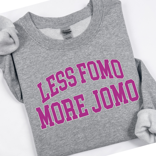 Gray sweatshirt with pink text 'LESS FOMO MORE JOMO' on a white background