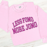 Pink sweatshirt with 'LESS FOMO MORE JOMO' text on a light wooden surface
