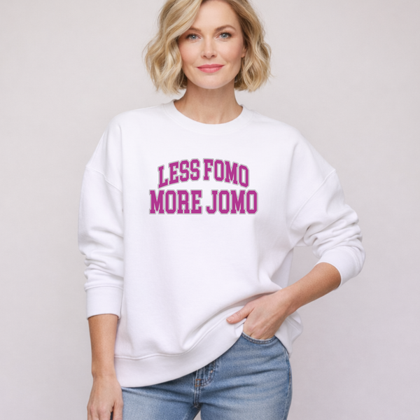 A woman wearing a white sweatshirt with 'LESS FOMO MORE JOMO' text on a plain background