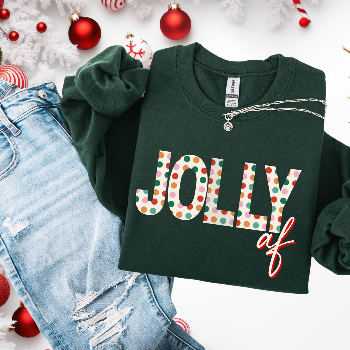 Green sweatshirt with 'Jolly af' text on a white background with Christmas decorations.