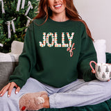 Person wearing a green sweatshirt with 'Jolly AF' text, sitting in front of a Christmas tree.