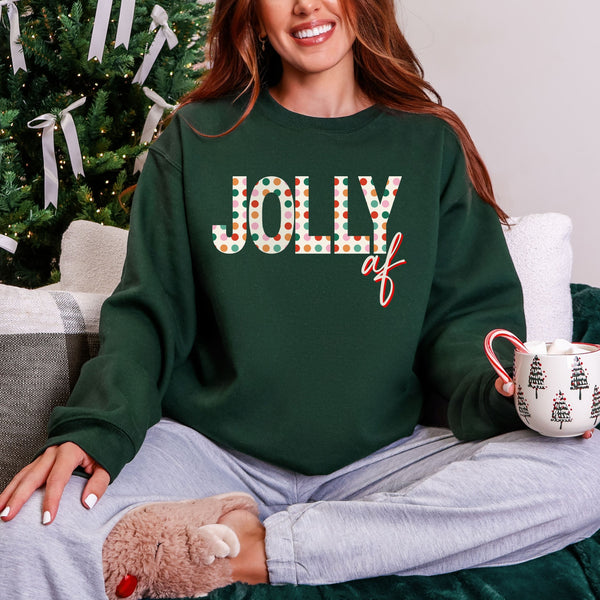 Person wearing a green sweatshirt with 'Jolly AF' text, sitting in front of a Christmas tree.