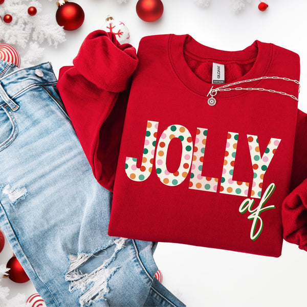 Red sweatshirt with 'Jolly af' text, paired with ripped jeans and Christmas decorations on a white background.
