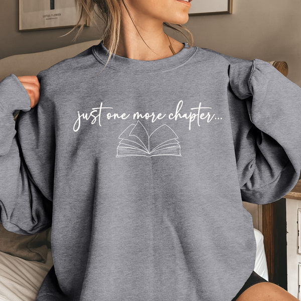 Person wearing a gray sweatshirt with 'just one more chapter...' text and book graphic.