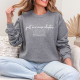 Person wearing a gray sweatshirt with 'just one more chapter...' text and book graphic.
