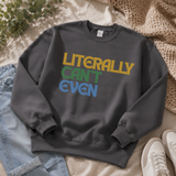 A dark gray crewneck sweatshirt with the text 'LITERALLY CAN'T EVEN' printed in yellow, green, and blue retro lettering. The sweatshirt is styled in a flat-lay arrangement on a beige blanket with light blue jeans, a knit throw blanket, and white sneakers.